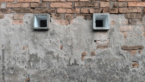 Brick and plaster wall with small square vents. Architectural texture and building background concept.
