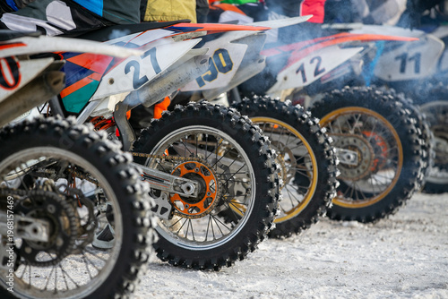 Row motocross dirt bikes lined up at starting line during winter racing competition