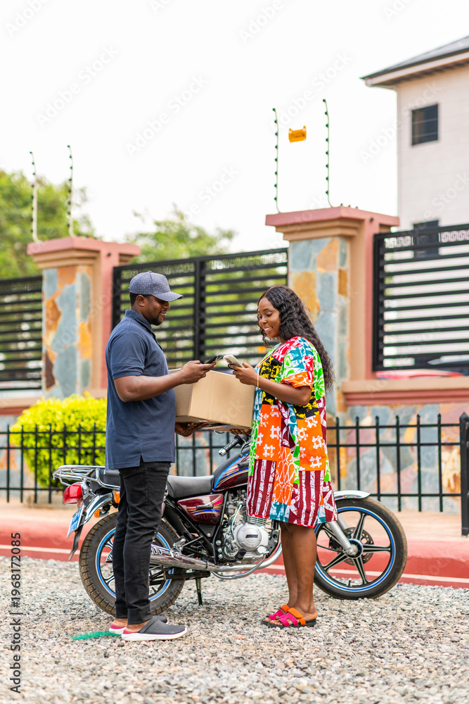 Obraz premium Delivery driver handing package to a woman making mobile payment