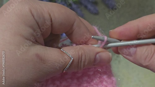 A textured, openwork knitting pattern made with colored yarn on a wooden surface with decorative flowers. Close-up of the knitting texture and pattern. Conceptual ideas for handicrafts