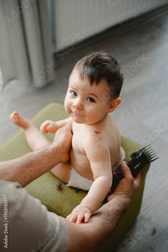 Soft light highlights a curious baby's face. Tiny hands grip a comb, eyes wide with wonder. Gentle touch soothes the child's skin. Warm tones frame the tender moment. Perfect for parenting, childcare