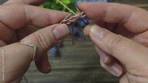 A textured, openwork knitting pattern made with colored yarn on a wooden surface with decorative flowers. Close-up of the knitting texture and pattern. Conceptual ideas for handicrafts