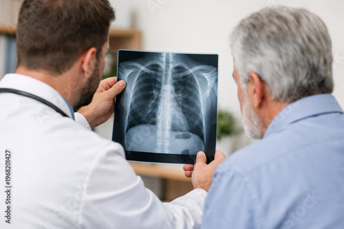 Doctor showing chest X-ray to senior male patient during medical consultation in a bright and professional clinic office