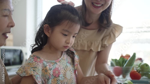 Daughter, mother and grandmother are preparing food together in the kitchen. Relationship, family, domestic life.