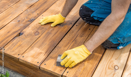 Worker applies wood stain with focused care