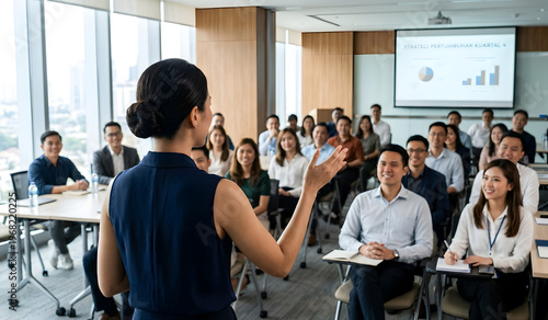 A woman speaks before an audience in a bright modern room.