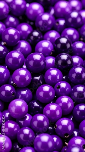 Close-up shot of a mass of spherical, shiny, deep purple beads filling the frame. Some beads are darker. Light creates highlights and shadows