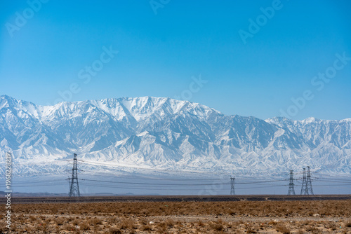 Canvas Print Snow covered Qilian Mountains in China with power lines in the foreground under