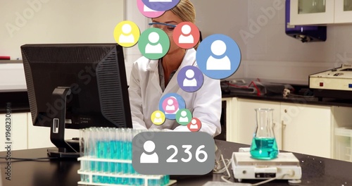 Woman lab scientist sitting behind monitor, 236 bubble popping, icons on face, logging tube results