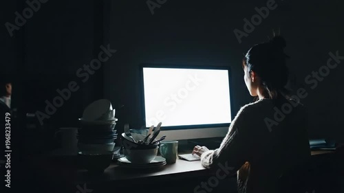 Woman working on computer at desk with dishes and city view transitioning from day to night
