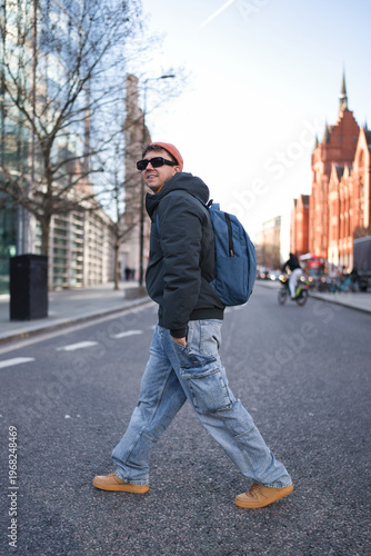 Photography Young man wearing casual jacket, cargo jeans, and sunglasses walking across a ci