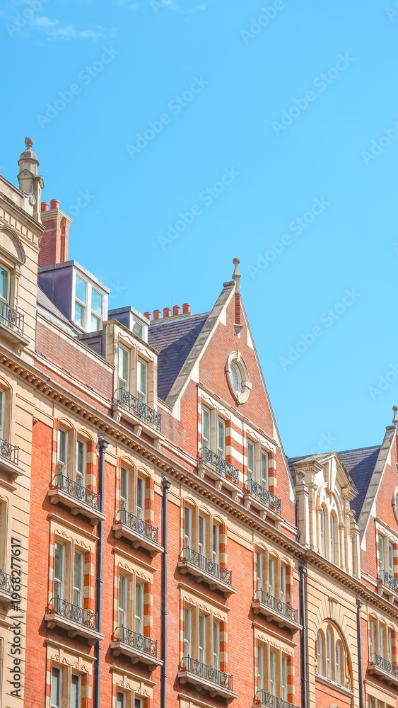 Fototapeta premium Historic brick buildings with ornate rooftops against a clear blue sky