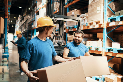 Warehouse workers lifting boxes in distribution center aisle