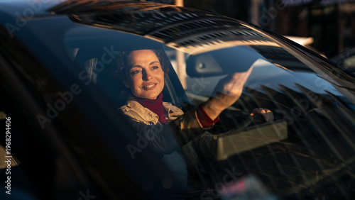 Fotografía Smiling woman driving a car during golden hour