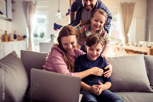 Принти на полотні Smiling family using laptop on living room sofa