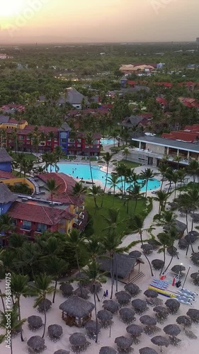Aerial flight above luxury resort with swimming pool tropical beach at sunset