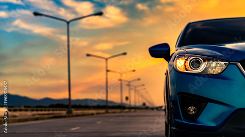 Obraz na płótnie Blue compact SUV car open headlamp light parked on concrete road near the mountain at sunset with beautiful sky and clouds
