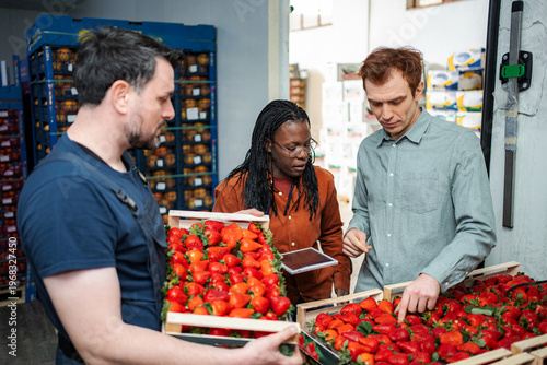 Fotografie Workers inspecting fresh strawberries for quality control in warehouse