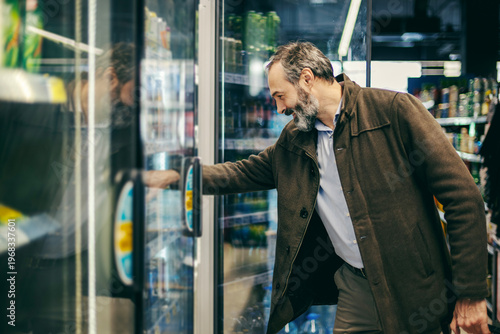 Фотография Man choosing beverage from refrigerated supermarket display