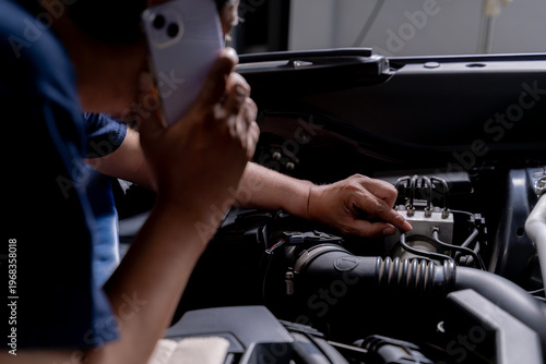 Obraz na plátně A young man fixes his car and calls a mechanic for assistance, showing problem solving, DIY effort, and seeking expert support
