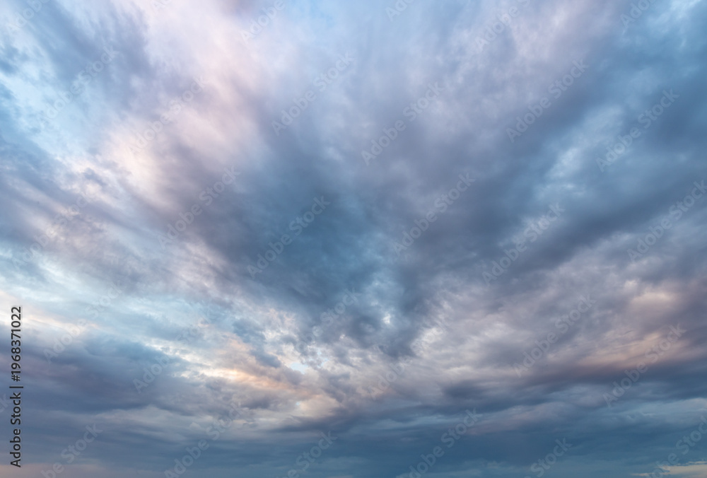 Obraz premium Dramatic clouds swirl above with soft blue and pink hues