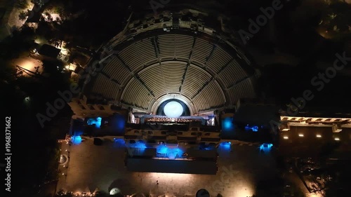Aerial drone top down still night video of iconic Odeon of Herodus Atticus built in the slopes of Acropolis hill, Athens historic centre, Attica, Greece