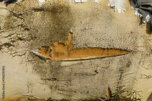 Torn and weathered vintage vinyl seat with exposed foam. Close-up of a damaged, cracked cream-colored upholstery showing yellow inner foam and heavy staining. Ideal for concepts of decay