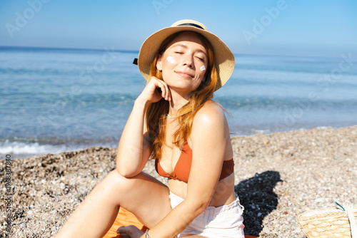 Schilderij op canvas Woman applying sunscreen to face enjoying beach vacation