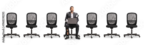 Businessman in a ripped suit with a laptop computer and many empty office chairs