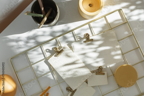 Overhead view of an aesthetic gold wire mood board with blank textured paper mockups and sun shadows.
