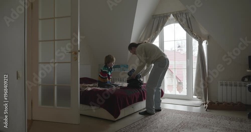 Man puts warm clothes on child. Dad help child to dress at home. 4K 10-bit