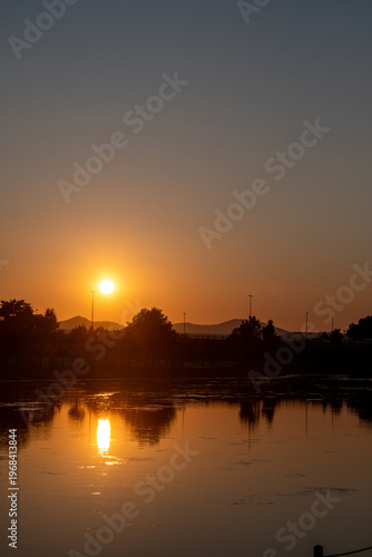 美しい夕日を映す公園の池の水面

