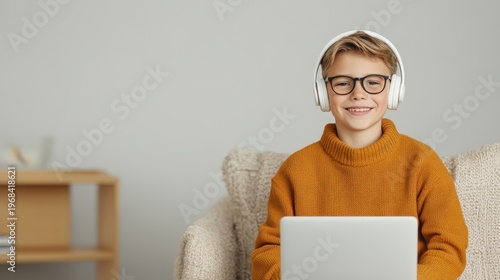 Happy boy wearing headphones glasses using laptop online learning studying home education technology child