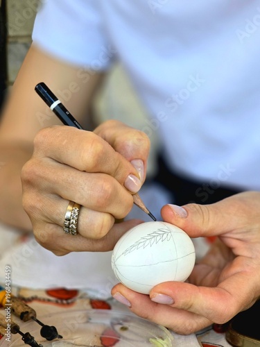 Close up of a man holding a pen. The color of eggs for Easter.