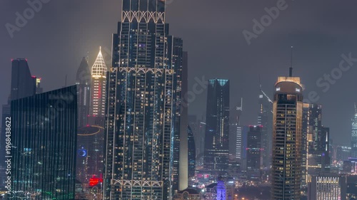 Illuminated modern skyscrapers, office towers, and hotels in the Dubai International Financial Centre DIFC. Aerial night view showing downtown traffic in time-lapse.
