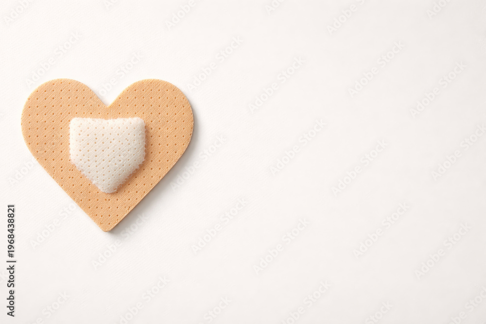 Fototapeta premium Adhesive plaster in heart shape. Symbol of psychological support, trauma recovery and soul healthcare.