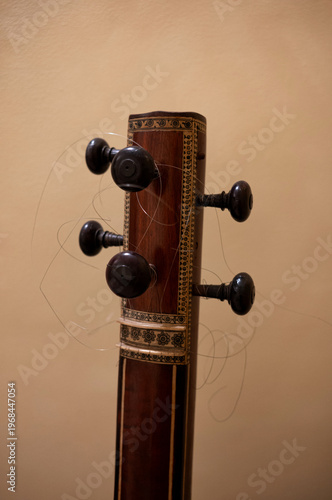 headstock, tuning pegs and broken strings of a sitar or veena, strings are broken and coiled in a mess