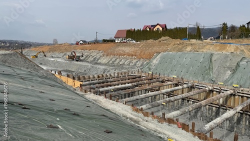 Construction of railway line LK104 with advanced ground stabilization and engineering structures. Geotechnical works including pile walls, soil reinforcement, ground nails, and slope protection system
