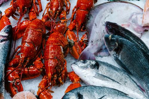 Seafood selection with red lobsters and fresh fish on ice. Top view of a luxury market display featuring gourmet crustaceans and silver sea bream at a traditional fish stall
