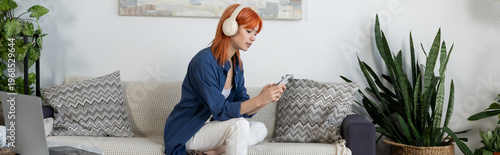 Fotografía Young woman with red hair enjoys leisure time in a stylish modern living room