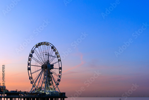 Fotografie a ferries wheel with lighting on in the sunset orange blue sky, background image