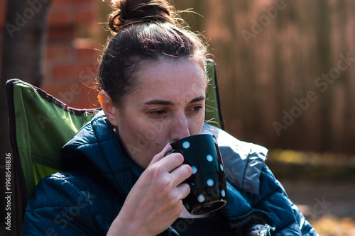 Young girl drinking coffee in the backyard on a sunny spring day