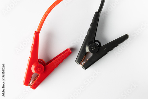 Red and black alligator clips for battery connection on white background