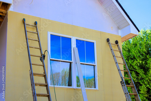 фотографія Ladders are leaned against side of house as workers plan to paint exterior after