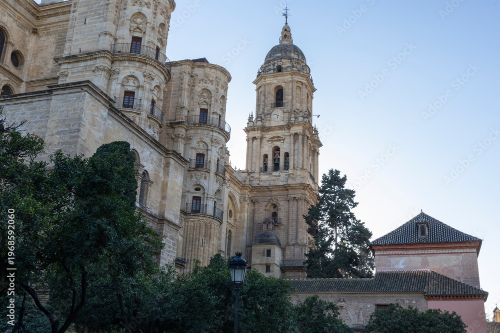 Fototapeta premium Church towers stand tall in Malaga Spain under clear sky during late afternoon