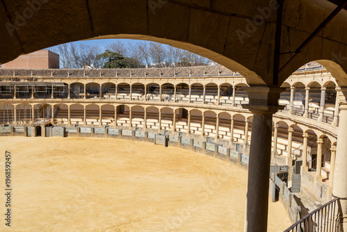 Plaza de Toros in Ronda shows empty arena with covered seating and clear sky on a sunny day