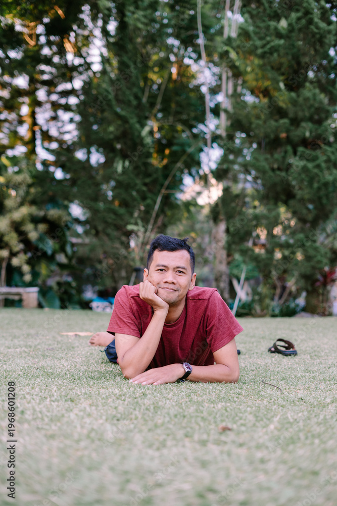 Fototapeta premium Relaxed man lying on grass with head resting on hands