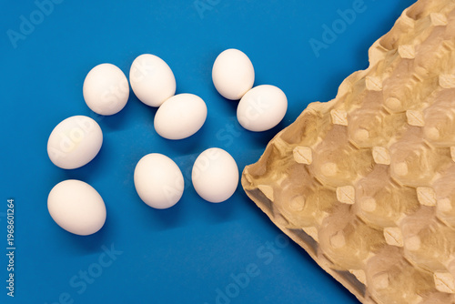 Nine white chicken eggs on blue background,
