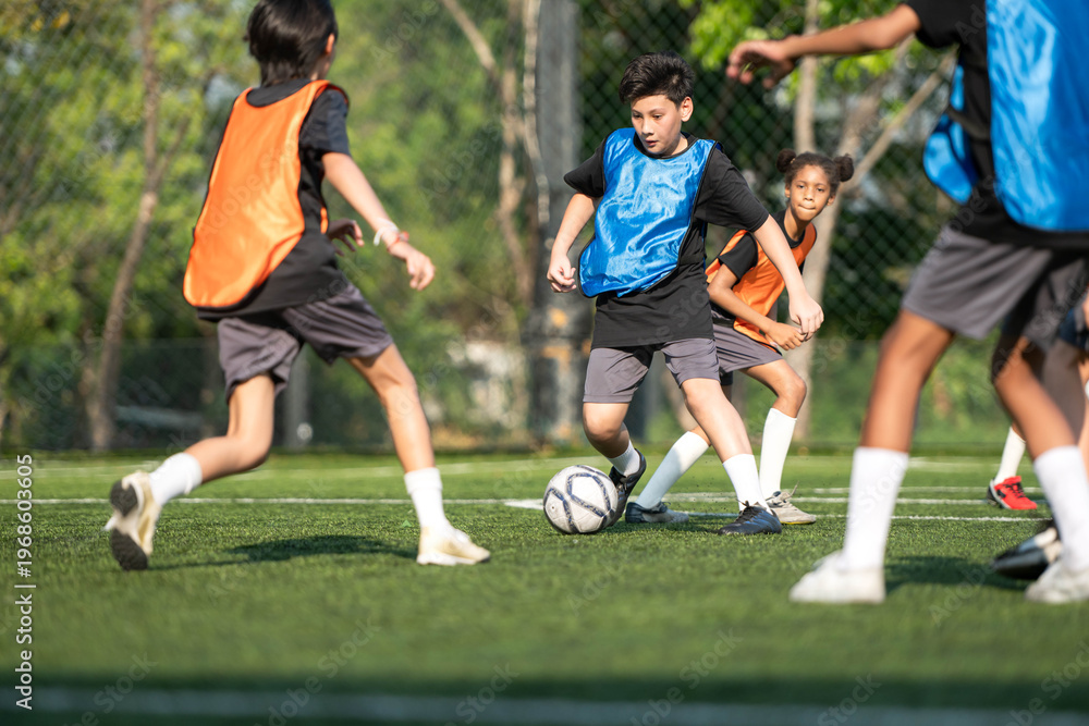 Fototapeta premium Group of international school kids playing soccer together on the field