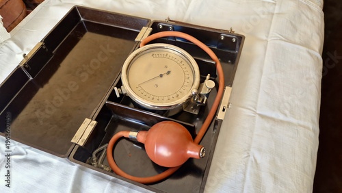 Foto Antique aneroid sphygmomanometer laying in its opened case on white cloth